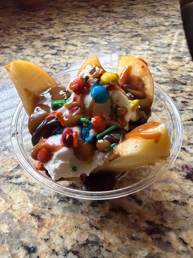 Apple slices with caramel, chocolate, whipped cream, candy-coated chocolates and sprinkles